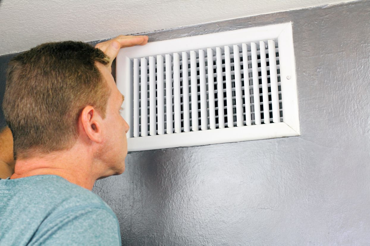 Homeowner inspecting air vent