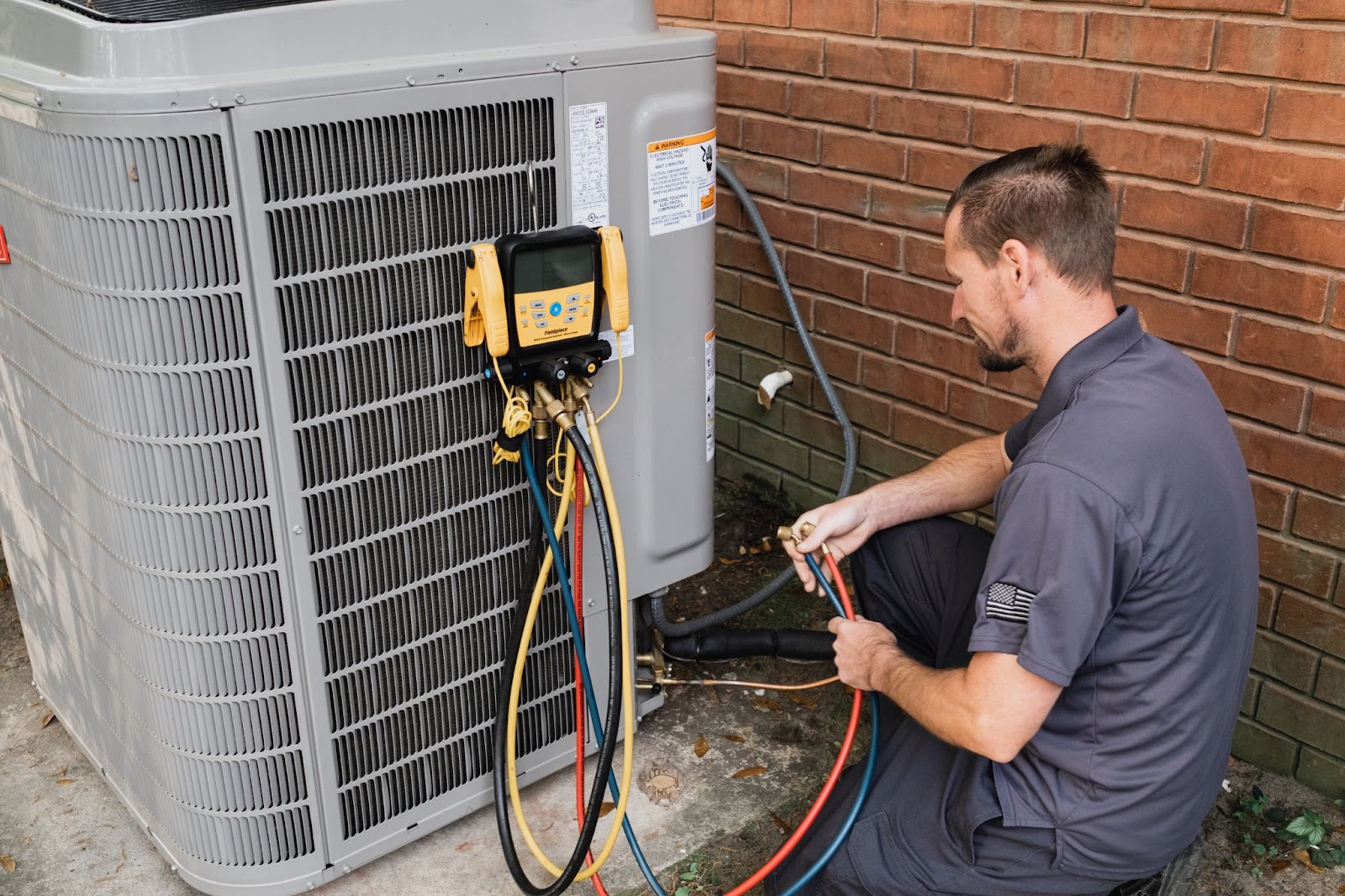 Indoor Climate Experts | Technician servicing residential HVAC unit.